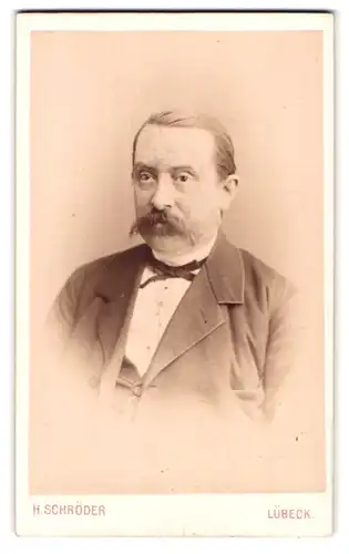 Fotografie H. Schröder, Lübeck, Beckergrube 150, Portrait Herr im Anzug mit Fliege und Walrossbart