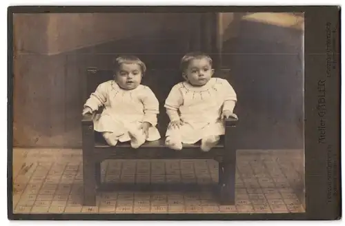Fotografie Atelier Gäbler, Leipzig, zwei Kleinkinder in gleichen Kleidern auf einer Bank