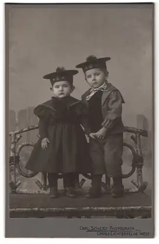 Fotografie Carl Scherz, Gross-Lichterfelde, Portrait junges Geschwisterpaar im Kleid und Anzug mit Matrosenmütze