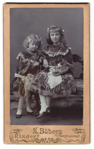 Fotografie H. Böbers, Berlin, Portrait zwei Mädchen im Samtkleidern mit Haarschleifen