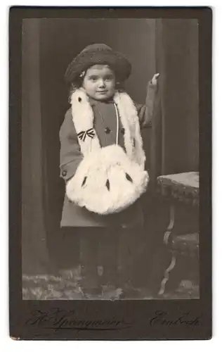 Fotografie H. Springmeier, Einbeck, Portrait süsses kleines Mädchen im Winterkleid mit Pelzhandtasche, 1915