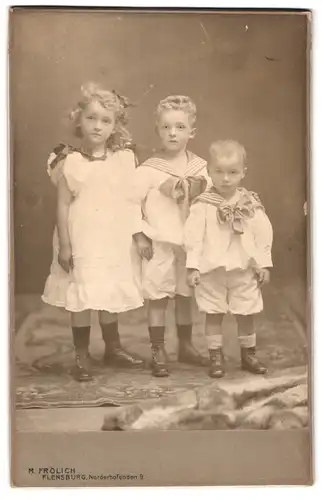 Fotografie M. Frölich, Flensburg, Norderhofenden 9, Portrait drei Geschwister in Matrosenanzügen und Kleid mit Locken