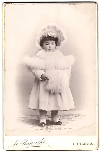 Fotografie M. Rupricht, Coblenz, Portrait kleines Mädchen im weissen Winterkleid mit Muff und Haube