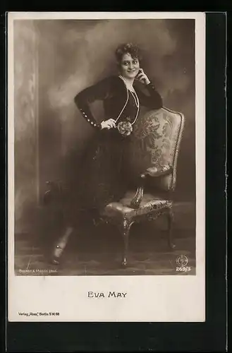 AK Schauspielerin Eva May posiert am Stuhl im langen schwarzen Kleid