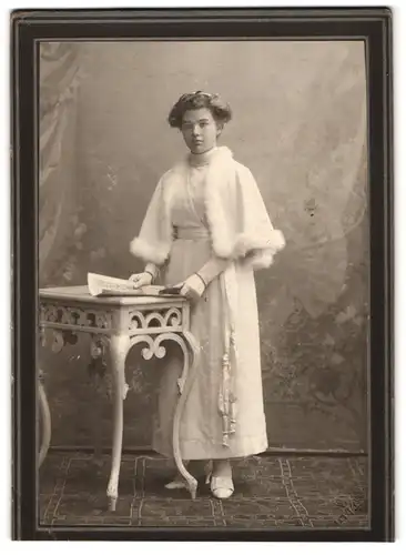 Fotografie und Ort unbekannt, Portrait junge Frau im weissen Kleid mit Pelzbesatz und Handschuhen