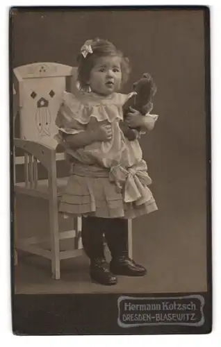 Fotografie Hermann Kotzsch, Dresden, niedliches Mädchen Elisabeth Wagner im Kleidchen mit ihrem Teddy im Arm