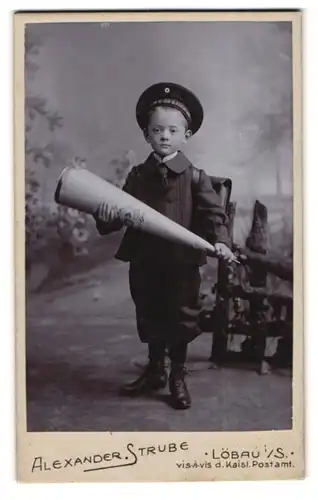 Fotografie Alexander Strube, Löbau i. S., junger Knabe im Anzug mit Zuckertüte und Mützenband SMS Baden, 1915