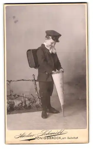 Fotografie Schmidt, Königsbrück, am Bahnhof, junger Knabe schaut in seine Zuckertüte zum ersten Schultag, Schulranzen