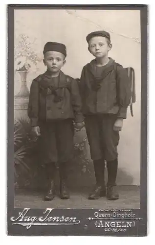 Fotografie Aug. Jensen, Quern-Dingholz, zwei Knaben in Schuluniform mit Schulranzen halten Händchen