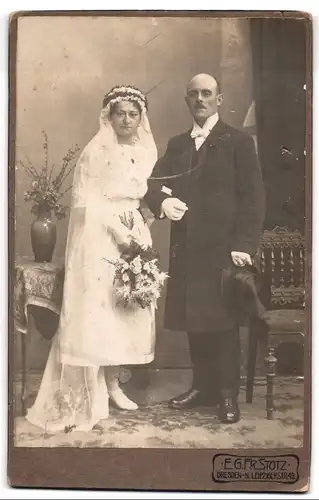 Fotografie E. G. Fr. Stotz, Dresden, Brautleute im weissen Hochzeitskleid und Anzug mit Zylinder, Brautstrauss