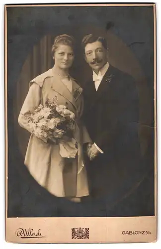 Fotografie A. Ullrich, Gablonz a. N., Hauptstr. 16, Eheleute am Hochzeitstag im Anzug und Mantel mit Brautstrauss