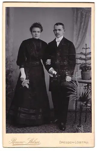 Fotografie Bruno Stelzer, Dresden, Portrait Brautleute im schwarzen Kleid und Anzug mit Melone in der Hand