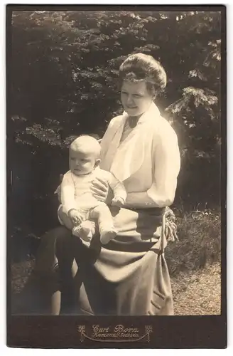 Fotografie Curt Born, Kamenz i. S., stolze Mutter mit ihrme Kind auf dem Schoss im Garten, Mutterglück