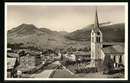 AK Riezlern, Strassenpartie mit Kirche und Blick auf die Berge