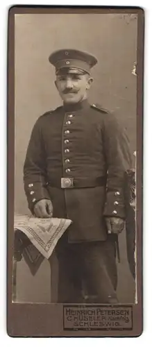 Fotografie Heinrich Petersen, Schleswig, Gedrungener Soldat mit Schirmmütze