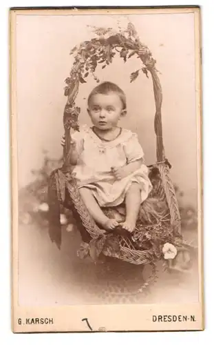 Fotografie G. Karsch, Dresden, niedliches Kind im Kleidchen sitzt im Weidenkorb