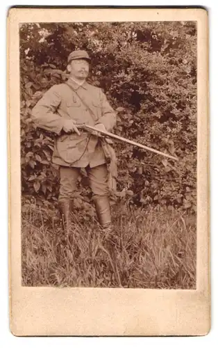 Fotografie unbekannter Fotograf und Ort, Mann als Jäger mit seiner Flinte im Garten posierend, 1903