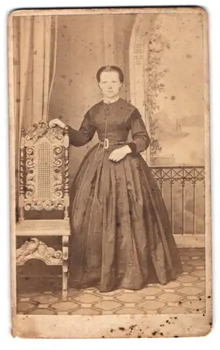 Fotografie A. Rossberg, Nossen, Neie Gasse 93, Portrait junge Frau im dunklen Biedermeierkleid stehend am Stuhl