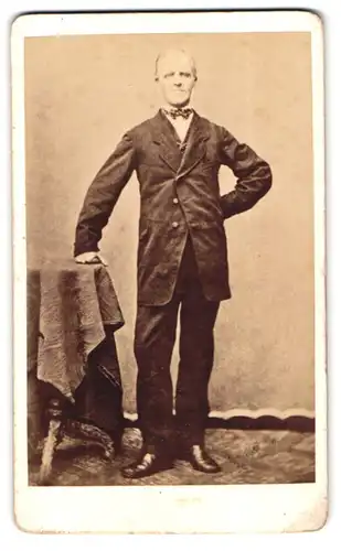 Fotografie unbekannter Fotograf und Ort, Portrait älterer Herr im Anzug posiert stehend im Atelier