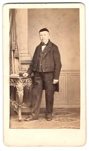 Fotografie August Brasch, Leipzig, Lindenstr. 7, Portrait älterer Her im dunklen Anzug mit Mütze auf dem Kopf