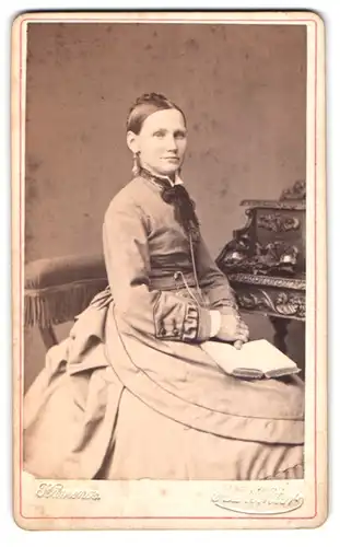 Fotografie A. Richter, Kamenz, junge Dame im hellen Kleid sitzend am Sekretär mit Buch auf dem Schoss