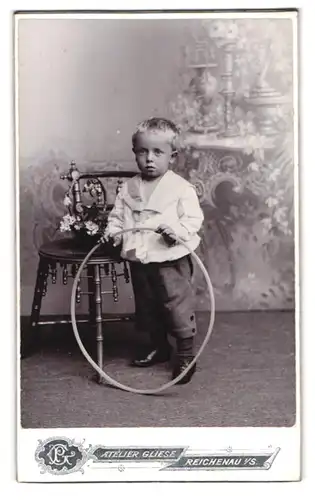 Fotografie Atelier Gliese, Reichenau i. S., Bub in feinen Kleidern mit Spielreif