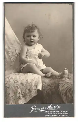 Fotografie James Aurig, Dresden-Blasewitz, Süsses Kleinkind im Hemd sitzt auf Fell
