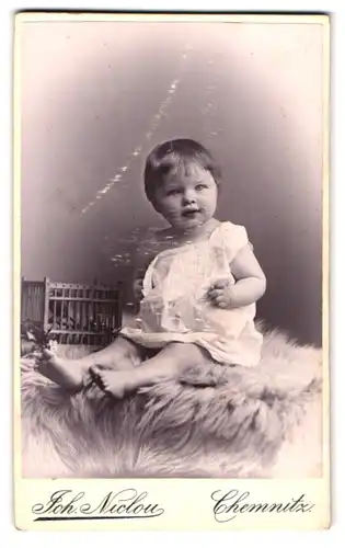 Fotografie Joh. Niclou, Chemnitz, König-Str. 5, Süsses Kleinkind im Hemd sitzt auf Fell