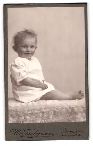 Fotografie W. Taubmann, Pirna a. E., Jacobäerstr. 6, Süsses Kleinkind im weissen Hemd mit nackigen Füssen