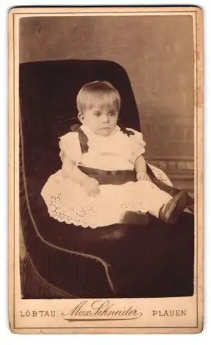 Fotografie Max Schneider, Plauen, Kleinkind in Spitzenkleidchen sitzt auf Sessel