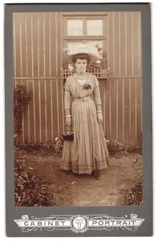 Fotografie unbekannter Fotograf und Ort, Portrait junge Dame im gestreiften Kleid mit Handtasche und Sommerhut im Garten