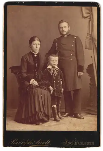 Fotografie Rudolph Arndt, Aschersleben, Uffz. in Uniform nebst Frau und Sohn im Atelier, Kriegsausmarsch