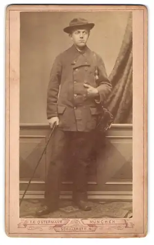 Fotografie F. X .Ostermay, München, Schillerstr. 4, Portrait junger Mann im Anzug auf der Walz mit Stock und Gepäck