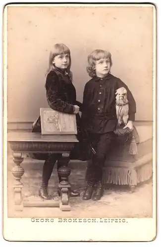 Fotografie Georg Brokesch, Leipzig, Portrait zwei niedliche Kinder im Samtkleid und Anzug mit Spielzeug Lama, 1891