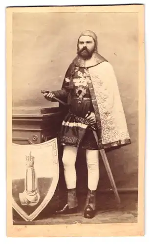 Fotografie unbekannter Fotograf und Ort, Portrait Schauspieler als Ritter im Kostüm mit Wappenschild mit Mittelfinger