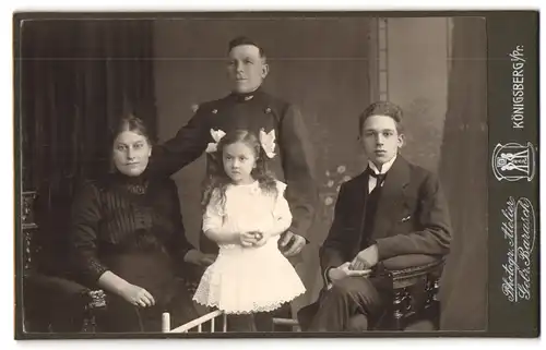 Fotografie gebr. Barasch, Königsberg i. Pr., Portrait Eisenbahner in Uniform mit Frau und Kindern im Atelier