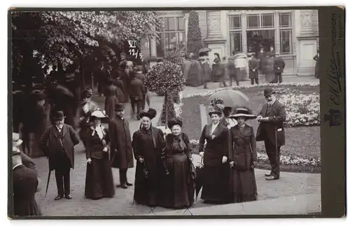 Fotografie E. H. Hies, Wiesbaden, Ansicht Wiesbaden, Herrschaften beim Flanieren in einem Park, 1911