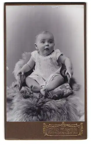 Fotografie Otto Martin, Dresden-Löbtau, Reisewitzerstr. 18, Portrait süsses Baby im weissen Hemdchen auf Fell sitzend