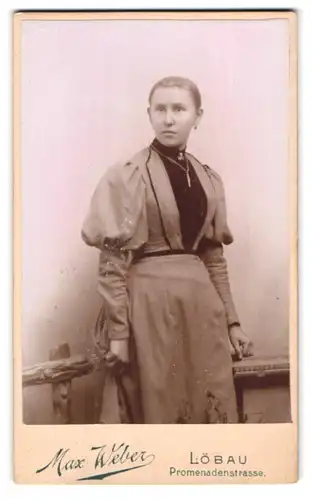 Fotografie Max Weber, Löbau, Promenadenstrasse, Portrait junge Frau mit Ohr- und Halsschmuck am Holzzaun stehend