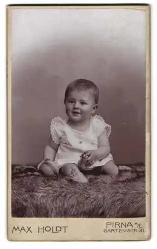 Fotografie Max Holdt, Pirna a. E., Gartenstr. 31, Portrait lächelndes Kleinkind mit Ball und Glocke in den Händen