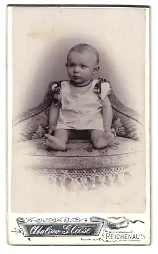 Fotografie Atelier Gliese, Reichenau i. S., Portrait süsses Baby mit Halskette im weissen Hemdchen
