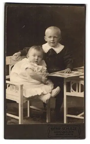 Fotografie Gebr. Schulze, Osnabrück, Grosse Str. 19, Portrait niedlicher Kinderpaar mit Buch am Tisch sitzend