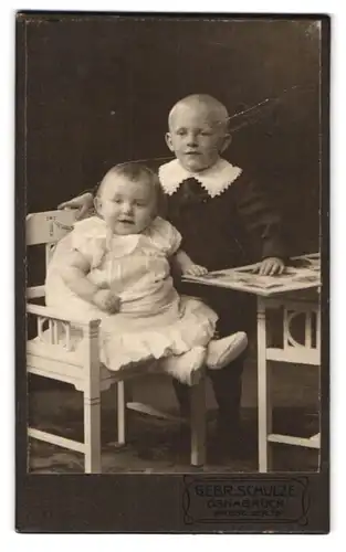 Fotografie Gebr. Schulze, Osnabrück, Grosse Str. 19, Portrait niedliches Kinderpaar mit Buch am Tisch sitzend