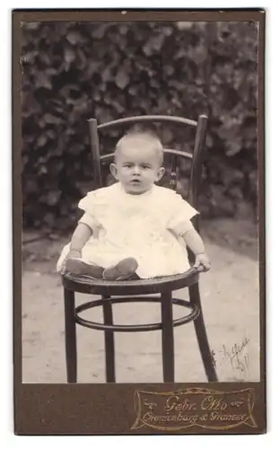 Fotografie Gebr. Otto, Oranienburg, Portrait blondes Baby auf einem Stuhl im Garten sitzend
