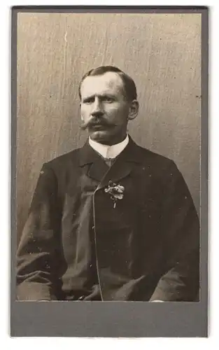 Fotografie Ferdinand Kiener, Bruck, Portrait stattlicher Herr mit Schnurrbart und Ansteckblume am Jackett