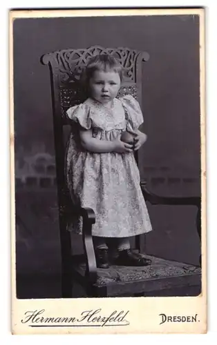 Fotografie Hermann Herzfeld, Dresden, Junges Mädchen in gemustertem Kleid hält einen Ball