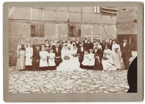 Fotografie Doppel-Hochzeit, Brautpaare & Gäste festlich gekleidet vor einem Fachwerkhaus um 1904