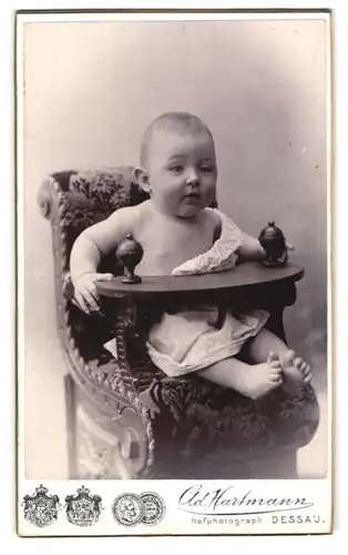 Fotografie Ad. Hartmann, Dessau, Franzstr. 25, Portrait süsses Baby im weissen Hemdchen im Kinderstuhl sitzend