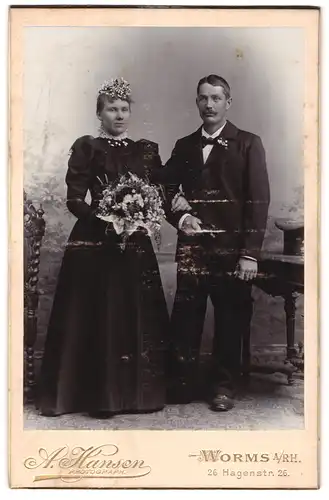 Fotografie A. Hansen, Worms a. Rh., Hagenstr. 26, Eheleute im schwarzen Hochzeitskleid und Anzug, Brautstrauss