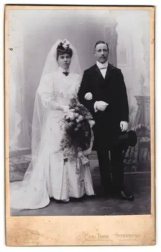 Fotografie Carl Timm, Harburg a. Elbe, Lindenstr. 18, Brautpaar im Hochzeitskleid und Anzug mit zylinder, 1906